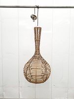 Front view of woven rattan teardrop pendant with cord and ceiling cap visible