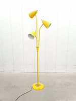 Full view of yellow three-light tree floor lamp standing on base