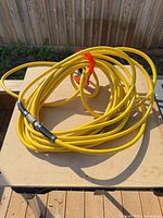 Coiled yellow air compressor hose on table