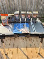 Group shot of four boxed bobble-heads, calendar and mini figure pack on table