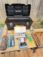 Overview of open black toolbox and all items spread on table