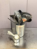 Utensils placed inside stainless steel holder with nested measuring cups alongside