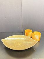 Leaf-shaped glass bowl with two amber glasses front view