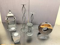 group shot of lantern, three candlesticks, two votive holders, ceramic vase