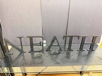 All five brown wooden letters N-E-A-T-H displayed on table