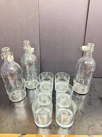 Two swing-top bottles and several tumblers on table