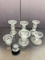 Front view of six clear glass candle holders, assorted heights