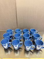Front view of all 12 blue mugs aligned