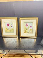 Both framed floral prints side by side on table