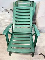 Two stacked green plastic slatted chaise lounges
