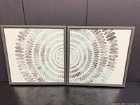Pair of square abstract prints with wood-look frames displayed side by side