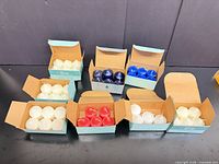 Eight open boxes showing assorted coloured votive candles
