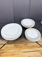 Stack of plain white dinner plates and two stacks of radial-rim salad/dessert plates