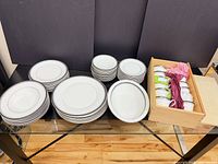 Full lot layout showing stacks of plates, bowls, oval platters, and wooden box of teacups