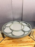 Angled view of round glass top coffee table showing segmented metal frame and base
