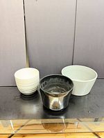 Three ceramic planters in white, black and gray displayed on table