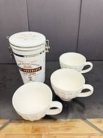 Overall lot showing three mugs and tin canister