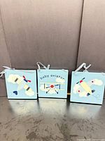 Front view of three square aviation-themed wooden plaques with ribbon hangers