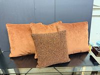 Three rust velvet pillows and one beaded pillow displayed front view