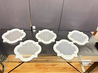 Five white quatrefoil mirrors laid out on table surface