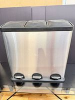 Front view of stainless steel triple-compartment bin showing three foot pedals