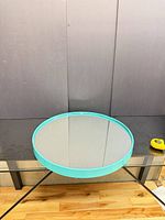 round tray with mirrored surface and turquoise metal frame shown flat on table
