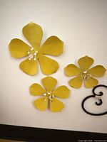 Three yellow metal flowers with black scroll accent