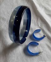 Bangle standing upright beside both hoop earrings