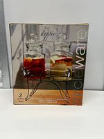 Front of retail box displaying two glass beverage dispensers on stand