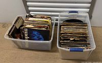 Two plastic bins filled with assorted vinyl records, sleeves visible