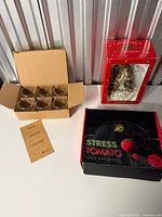 All items: boxed angel dispenser, boxed Stress Tomato ball, open box of six espresso glasses, paper leaflets