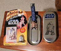 Front view of both items: sealed Action Masters R2-D2 figure and Episode I watch in tin