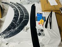 Overview of lot showing fender flares, trim pieces, wipers, filter, casters, hardware bag, garment rack parts