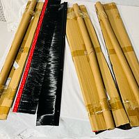 four black brush strips, two unpacked showing bristles and adhesive, two in cardboard sleeves