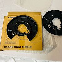Pair of black steel brake dust shields on packaging