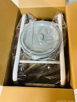 Boxed KMINA commode showing top of unit with bucket and lid in plastic