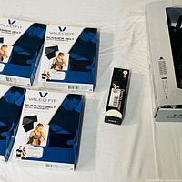 Overview showing three Valeo Fit slimmer belts, one WMK skin tag remover, one K&K curling iron in boxes