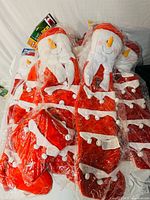 Stack of sealed red and white snowman stockings showing snowman heads and bell details