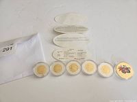 Six encapsulated coins/medallion with leaflet
