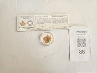 Coin with coloured maple leaves in capsule next to certificate open