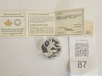 Coin in capsule beside certificate of authenticity, showing reverse design