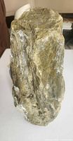 front view of tall green-brown stone showing texture and white mineral streaks