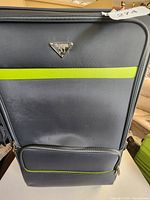 Front view of grey suitcase showing lime stripe and logo