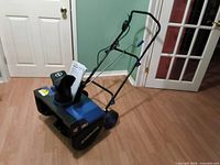 Front angled view of Snow Joe electric snowblower showing chute, wheels, handle and manual