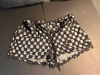 Full view of checkered Shein Curve shorts front displaying pattern, fringe edges, drawstring