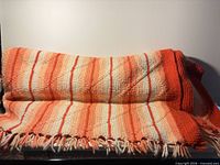 Full view of folded striped throw blanket showing colors, quilted stitching and fringe