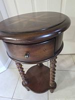 Full view of round mahogany end table showing drawer, barley twist legs, lower shelf