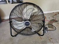 Front view of Lasko 20-inch floor fan showing blades, cage and brand badge