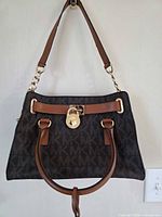 Front view of Michael Kors brown monogram satchel with shoulder strap and top handles