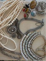 Overview of necklaces, rings, pearl strands and ring sizer on fabric background